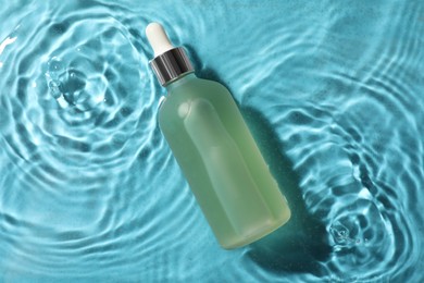 Photo of Bottle of hydrophilic oil in water on light blue background, top view