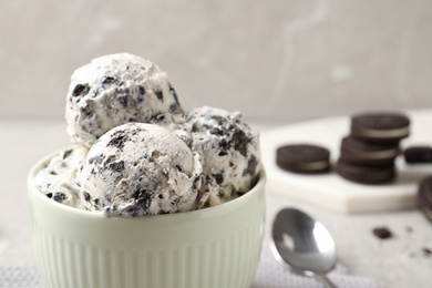 Bowl with ice cream and crumbled chocolate cookies on table, closeup. Space for text
