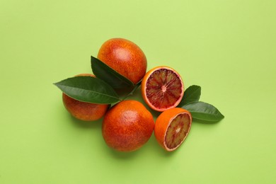 Photo of Ripe sicilian oranges and leaves on light green background, flat lay