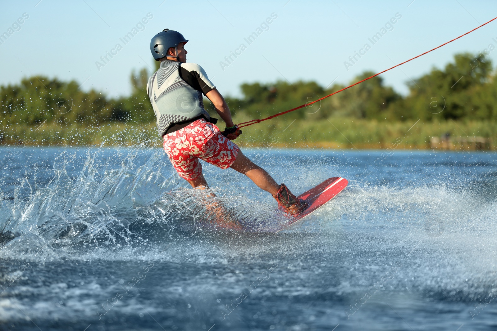 Photo of Teenage boy wakeboarding on river. Extreme water sport