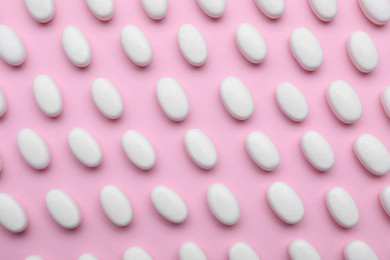 Photo of Many white dragee candies on pink background, flat lay