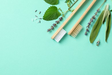 Photo of Flat lay composition with bamboo toothbrushes and herbs on turquoise background. Space for text