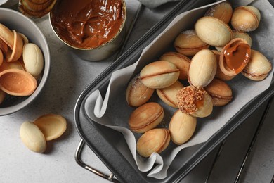 Delicious walnut shaped cookies with condensed milk on grey table, flat lay