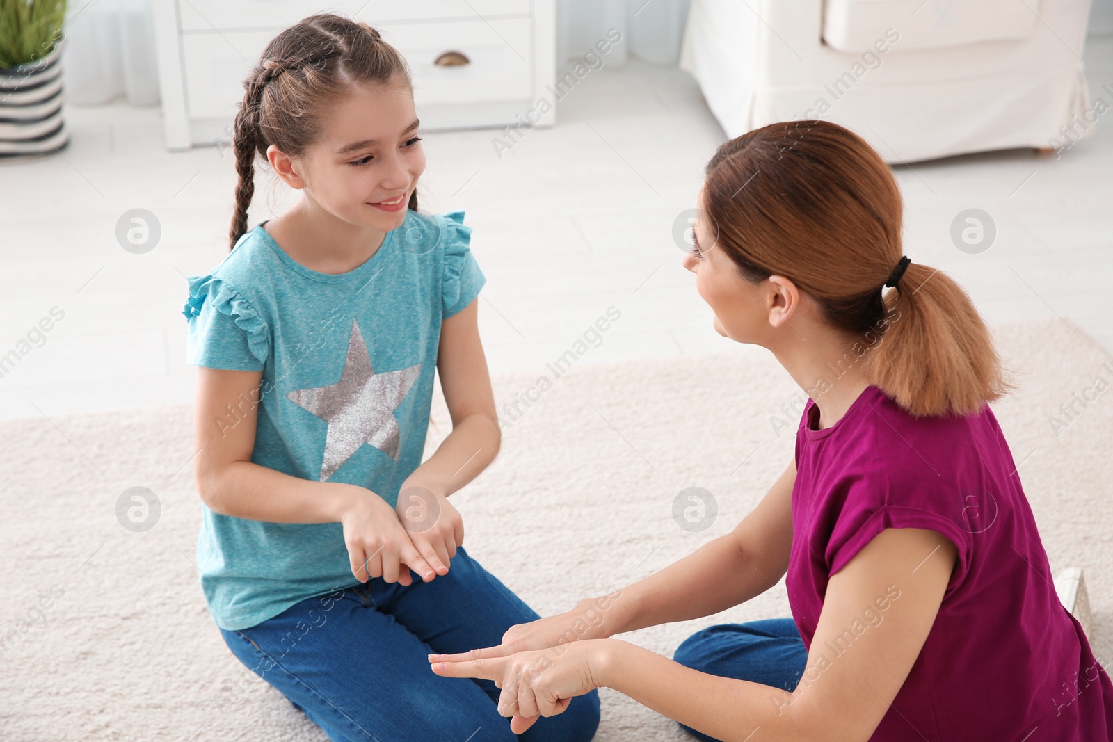 Photo of Hearing impaired mother and her child talking with help of sign language indoors