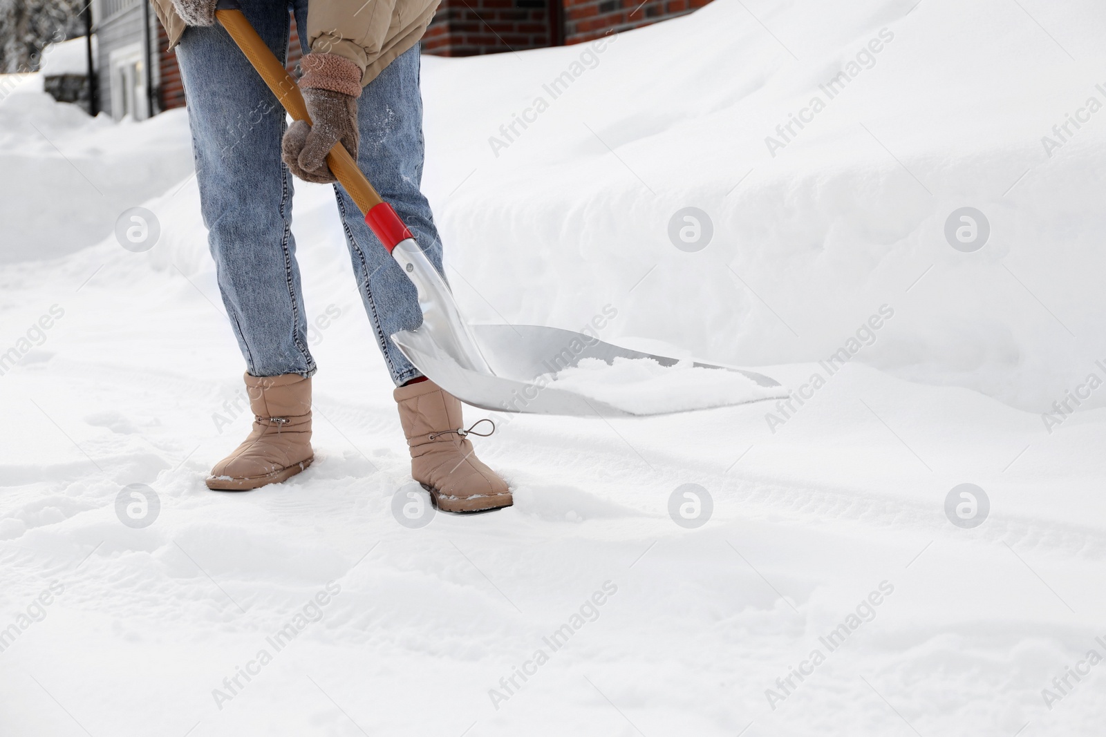 Photo of Woman removing snow with shovel outdoors, closeup