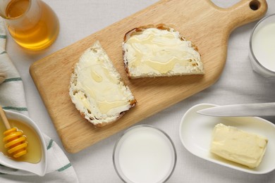 Photo of Slices of bread with butter, honey and milk on white table, flat lay