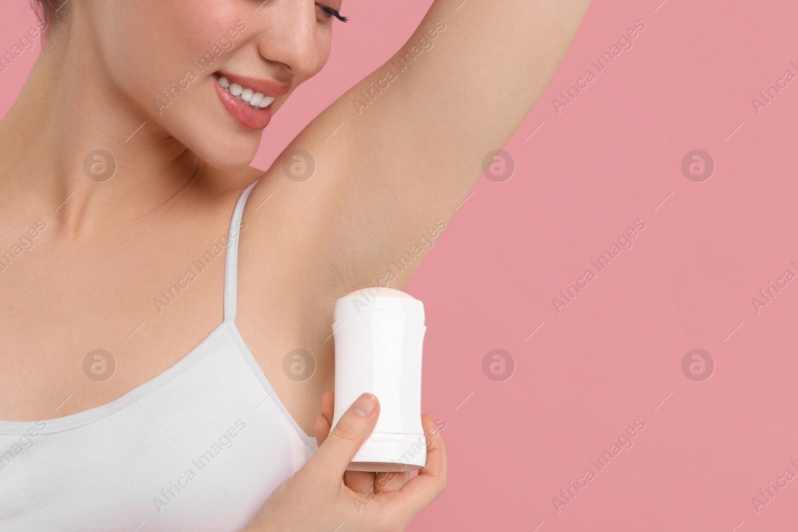 Photo of Beautiful woman applying deodorant on pink background, space for text