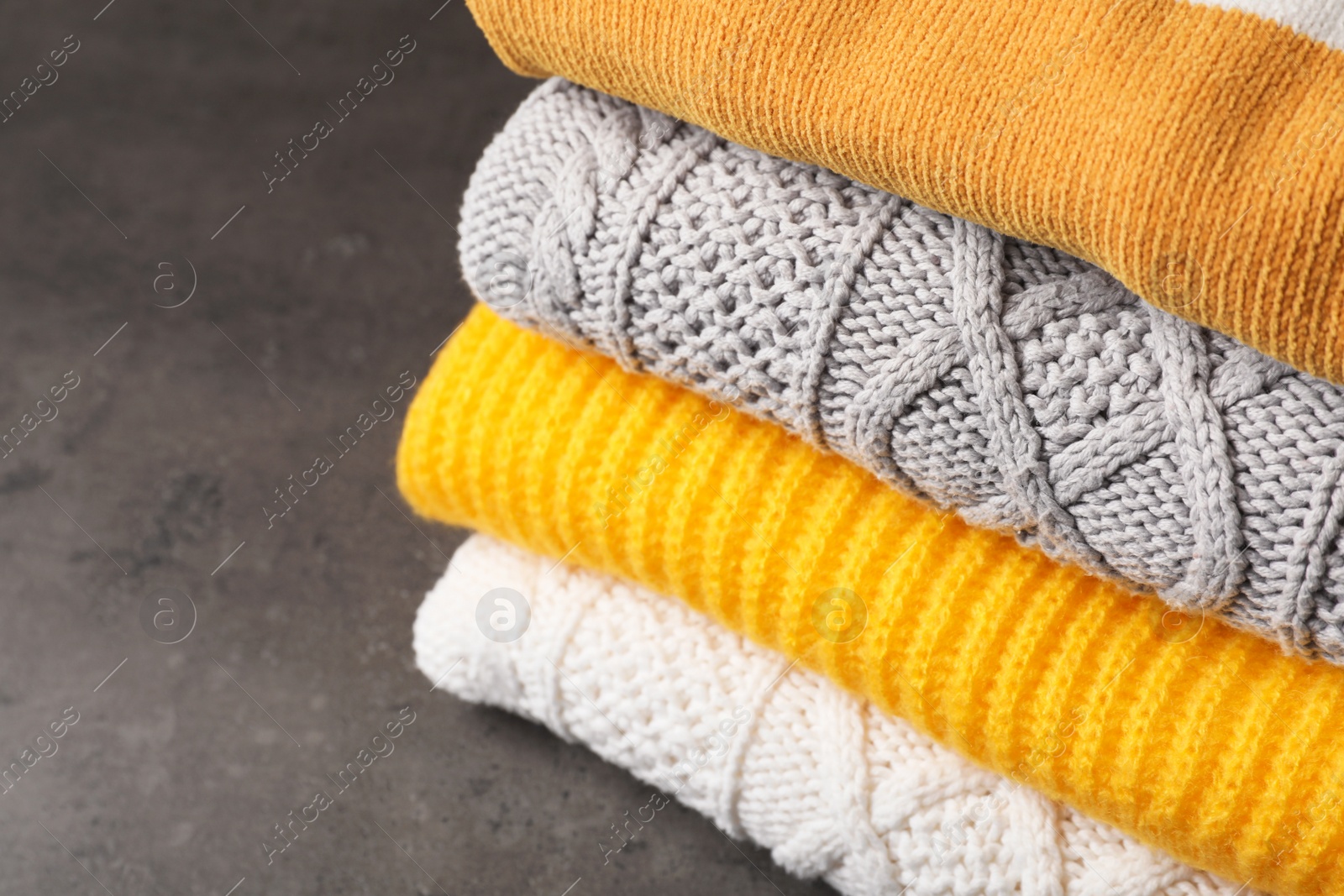 Photo of Stack of folded knitted sweaters on table, closeup. Space for text