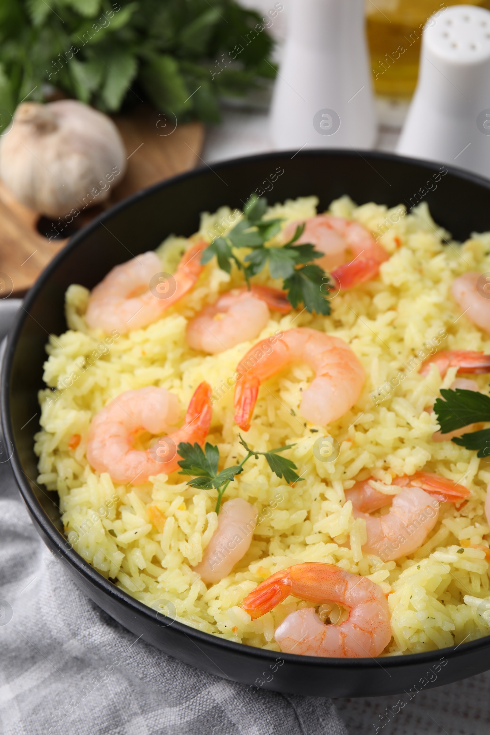 Photo of Delicious risotto with shrimps and parsley in bowl on table, closeup