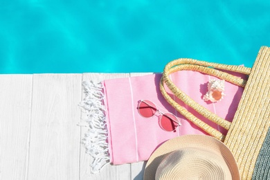Flat lay composition with beach accessories on wooden deck near swimming pool. Space for text