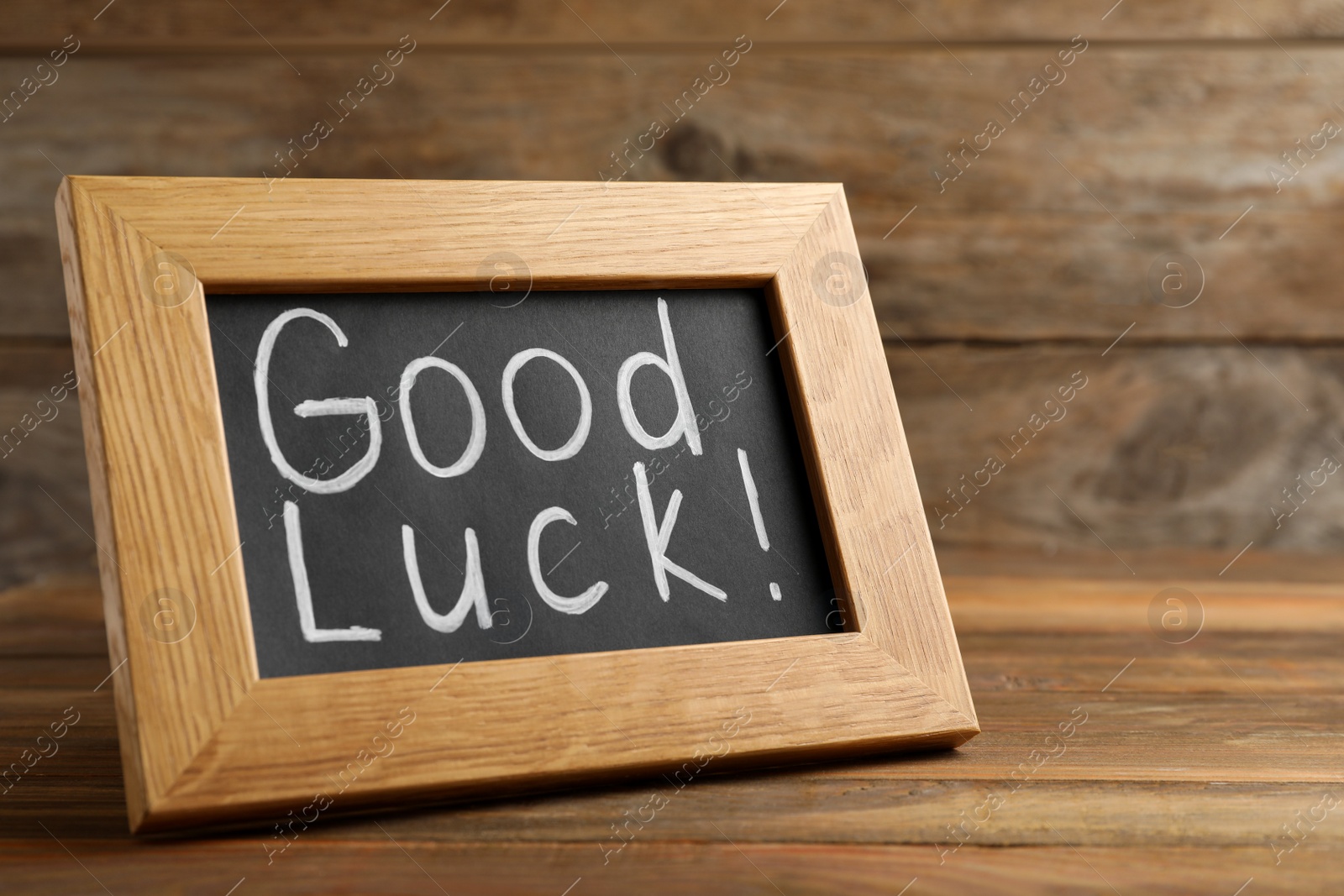 Photo of Blackboard with phrase GOOD LUCK on wooden table