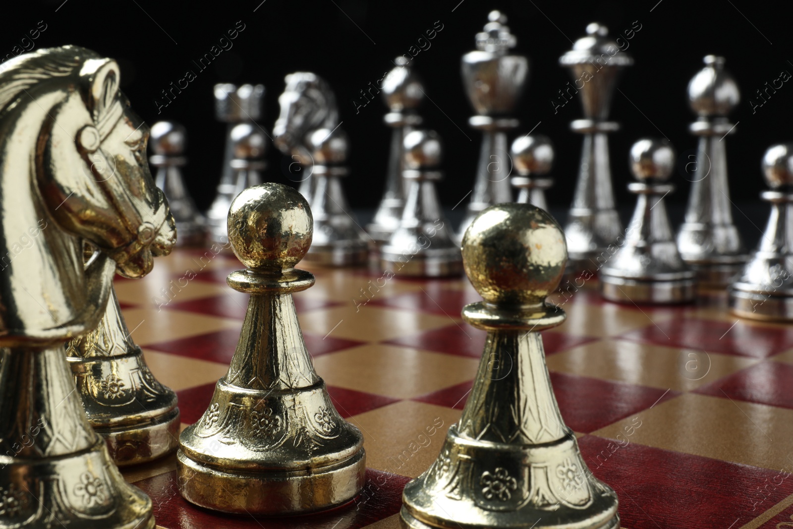 Photo of Chessboard with game pieces on black background, closeup