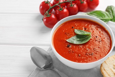 Photo of Delicious tomato cream soup in bowl on white wooden table, space for text