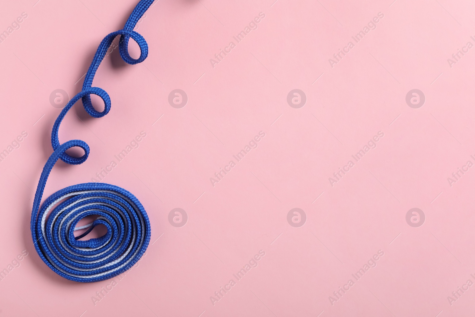 Photo of Blue shoelace on pink background, top view. Space for text
