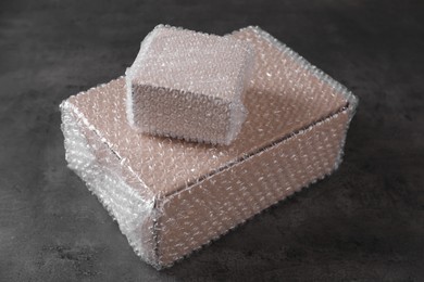 Photo of Cardboard boxes covered with bubble wrap on dark grey table