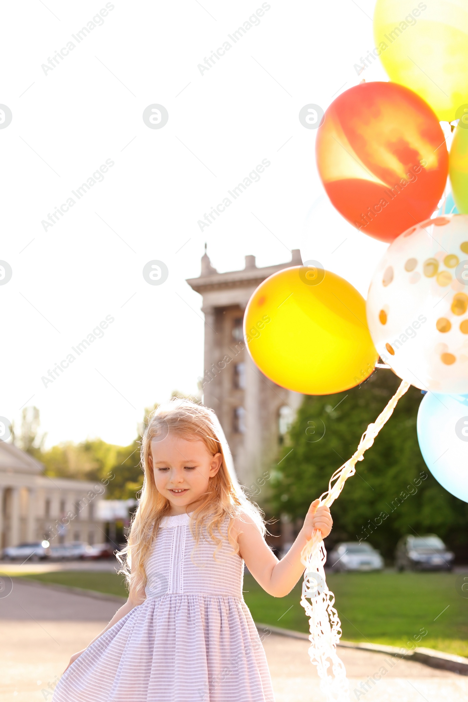 Photo of Cute little girl with colorful balloons outdoors on sunny day