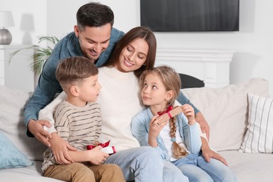 Photo of Happy family presenting each other with gifts on sofa at home