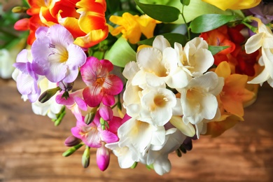 Photo of Beautiful bouquet of freesia flowers on table, closeup