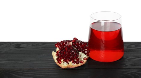 Photo of Refreshing pomegranate juice in glass and fruit on black wooden table against white background. Space for text