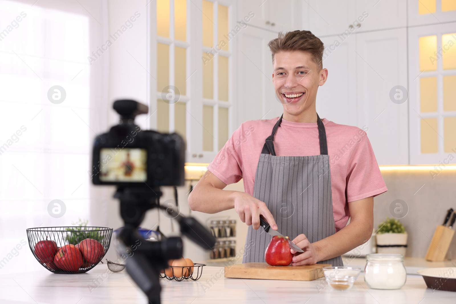 Photo of Smiling food blogger cooking while recording video in kitchen