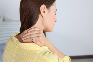 Photo of Woman suffering from neck pain in room
