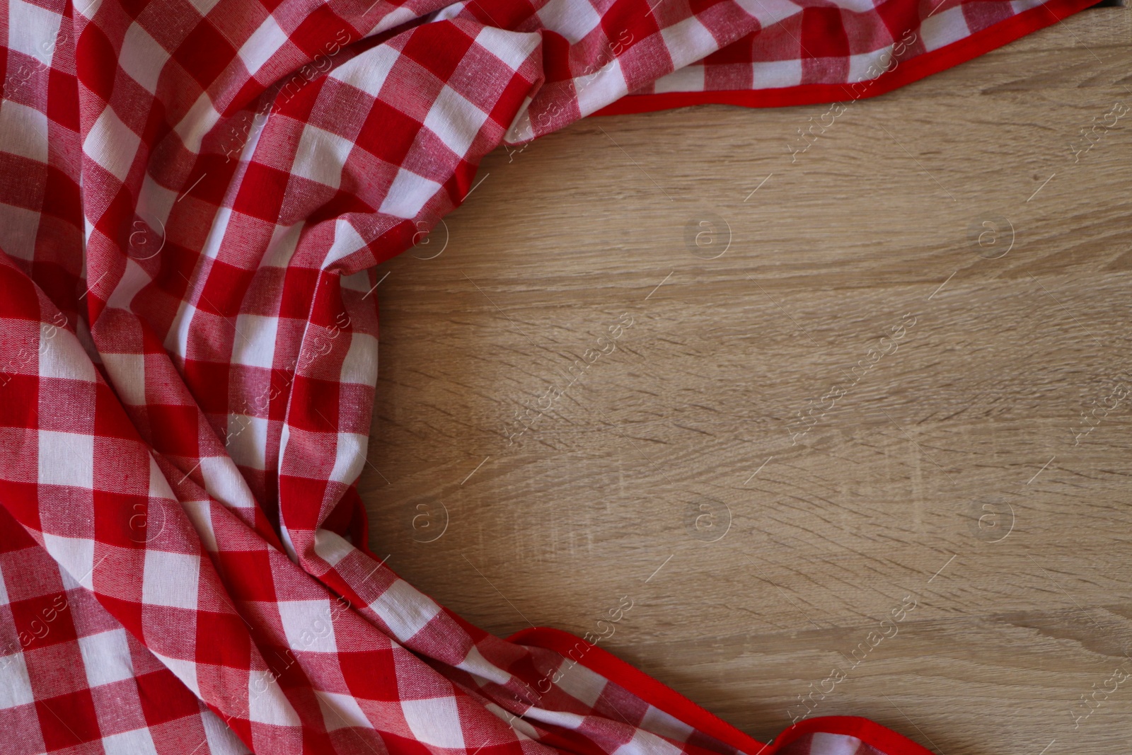 Photo of Checkered picnic cloth on wooden table, top view. Space for text