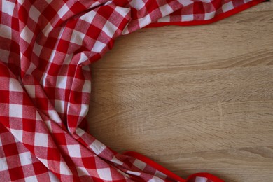 Photo of Checkered picnic cloth on wooden table, top view. Space for text