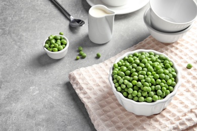 Photo of Bowl with delicious fresh green peas on table