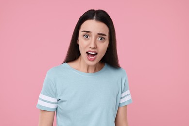 Portrait of surprised woman on pink background