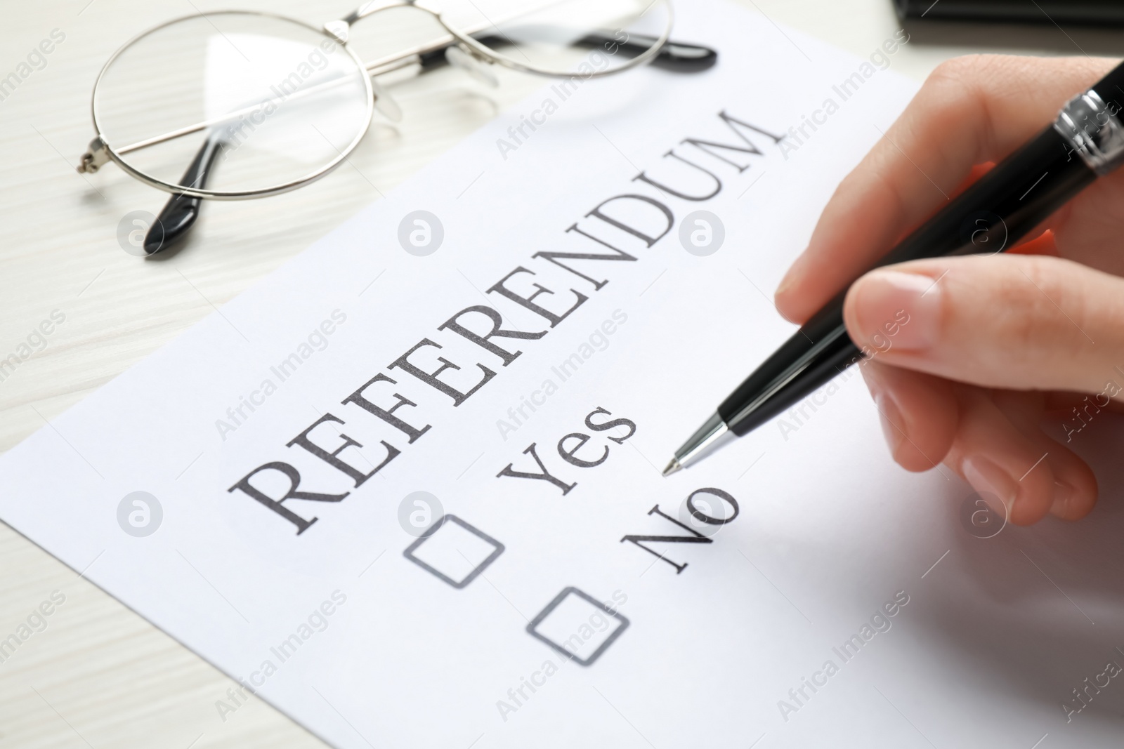 Photo of Woman with referendum ballot making decision at white table, closeup