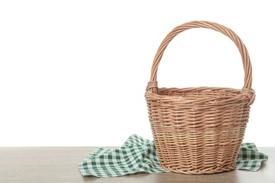 Photo of Empty wicker basket and cloth on wooden table against white background, space for text. Easter holiday