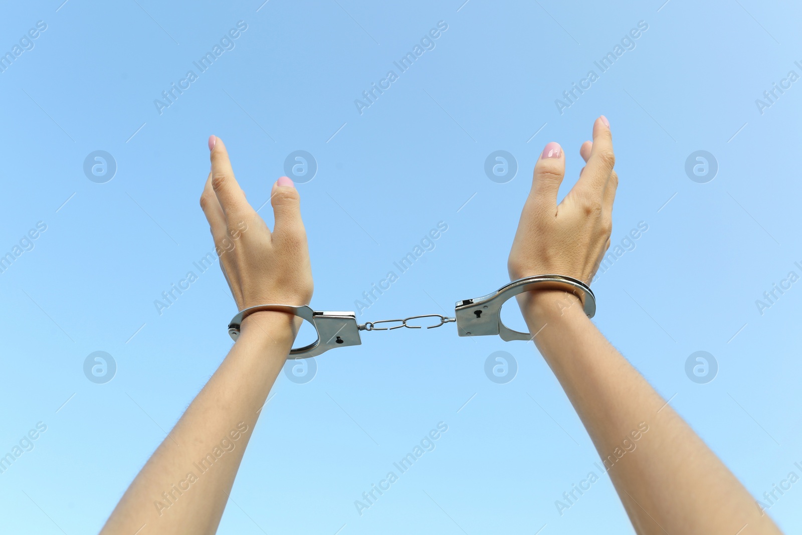 Photo of Woman in handcuffs against blue sky, closeup
