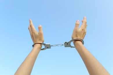 Photo of Woman in handcuffs against blue sky, closeup