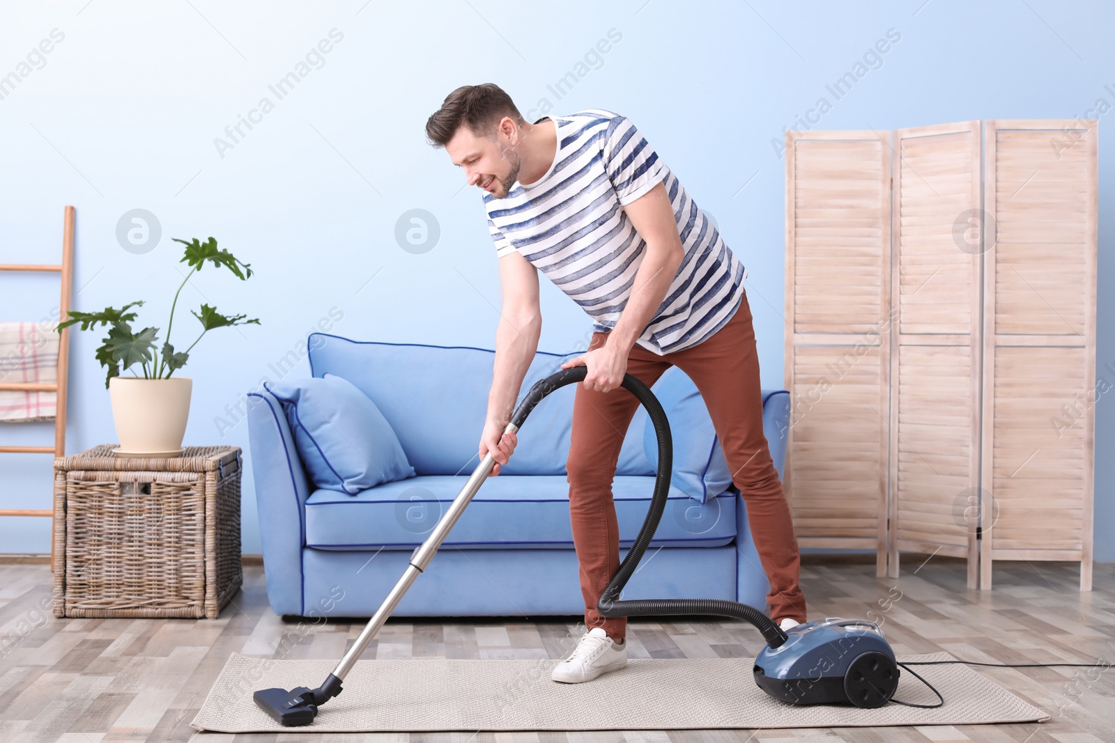 Photo of Mature man hoovering carpet with vacuum cleaner in living room