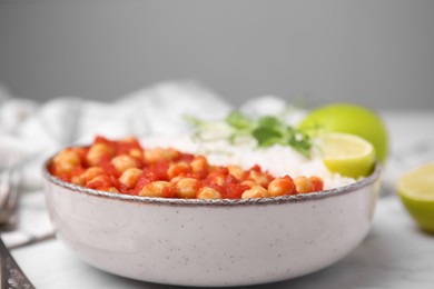 Photo of Delicious chickpea curry with rice in bowl on white marble table, closeup