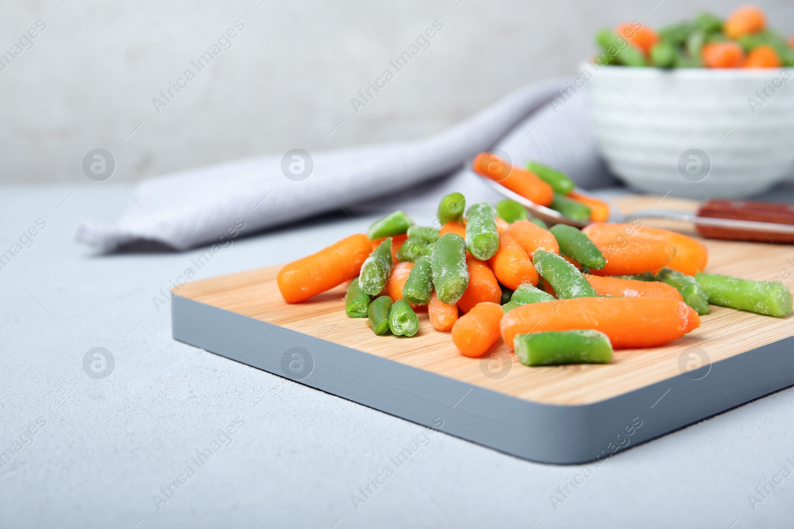 Photo of Wooden board with frozen vegetables on table