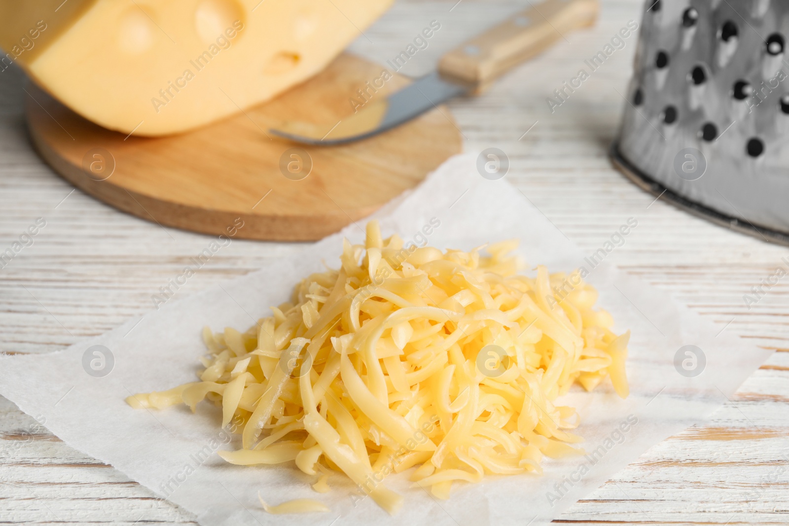 Photo of Tasty grated cheese on white wooden table