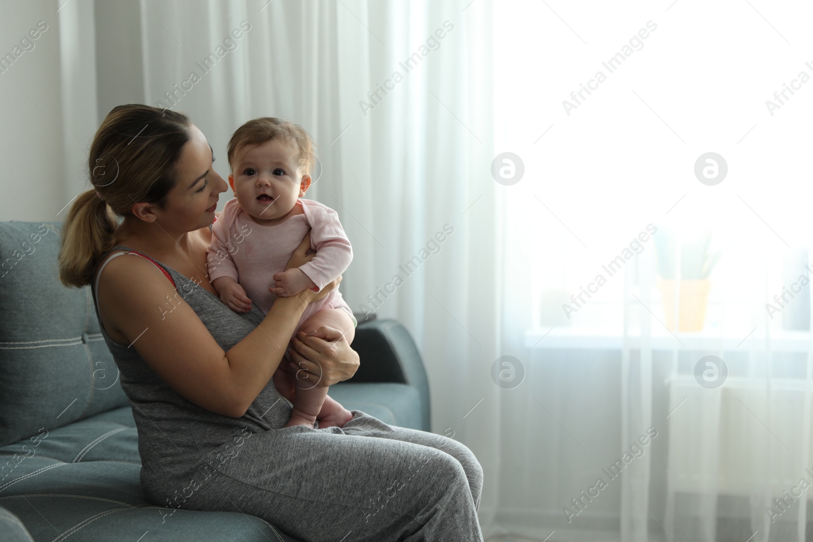 Photo of Young woman with her cute baby at home. Space for text