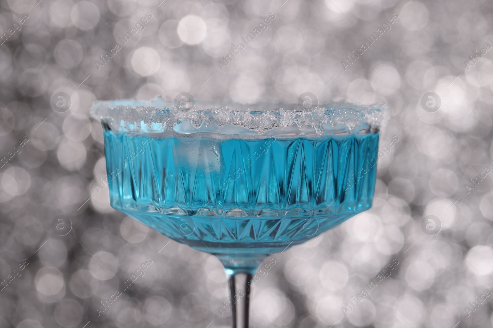 Photo of Glass of refreshing light blue drink against blurred background, closeup