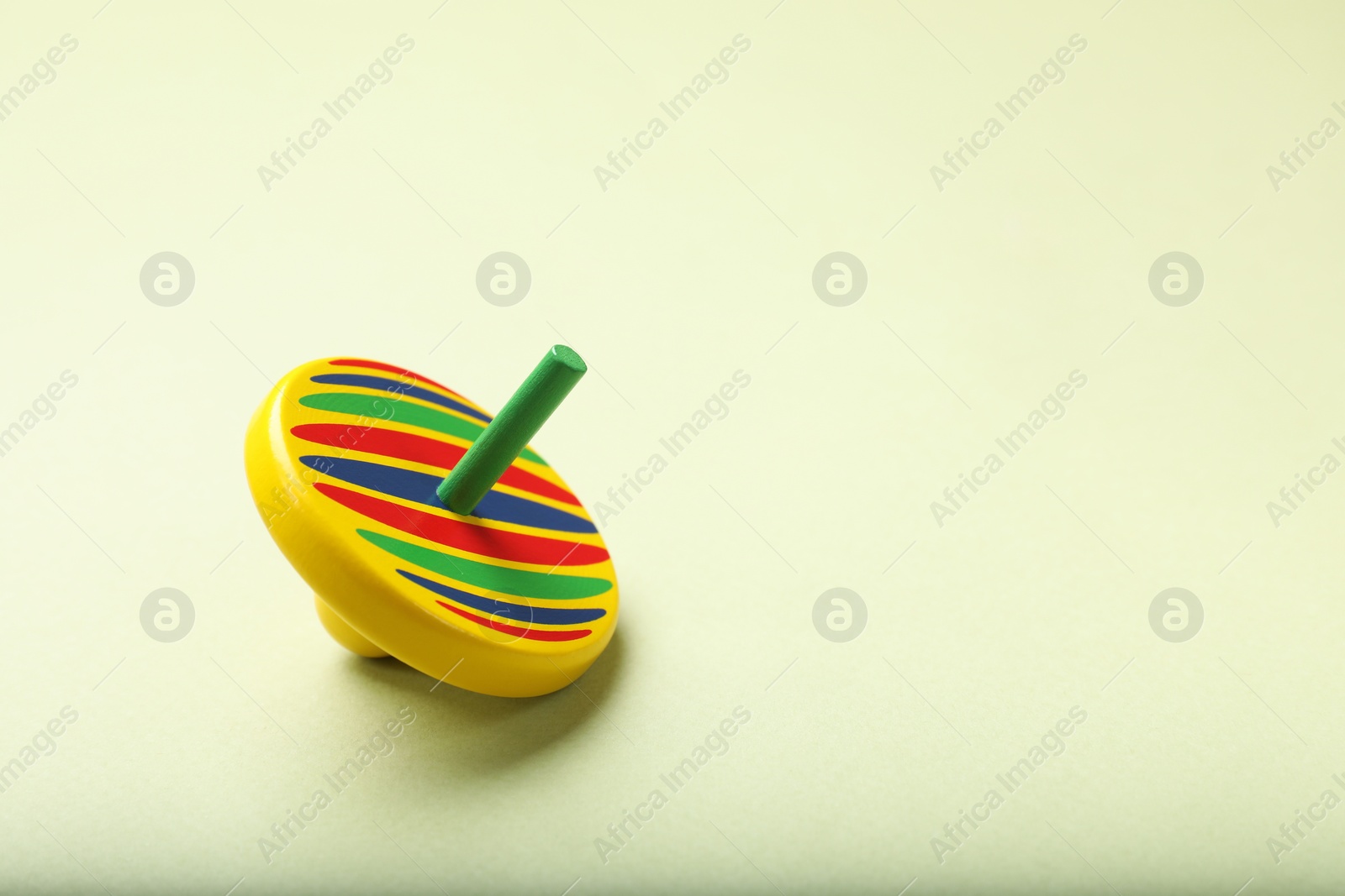 Photo of One colorful spinning top on green background, space for text