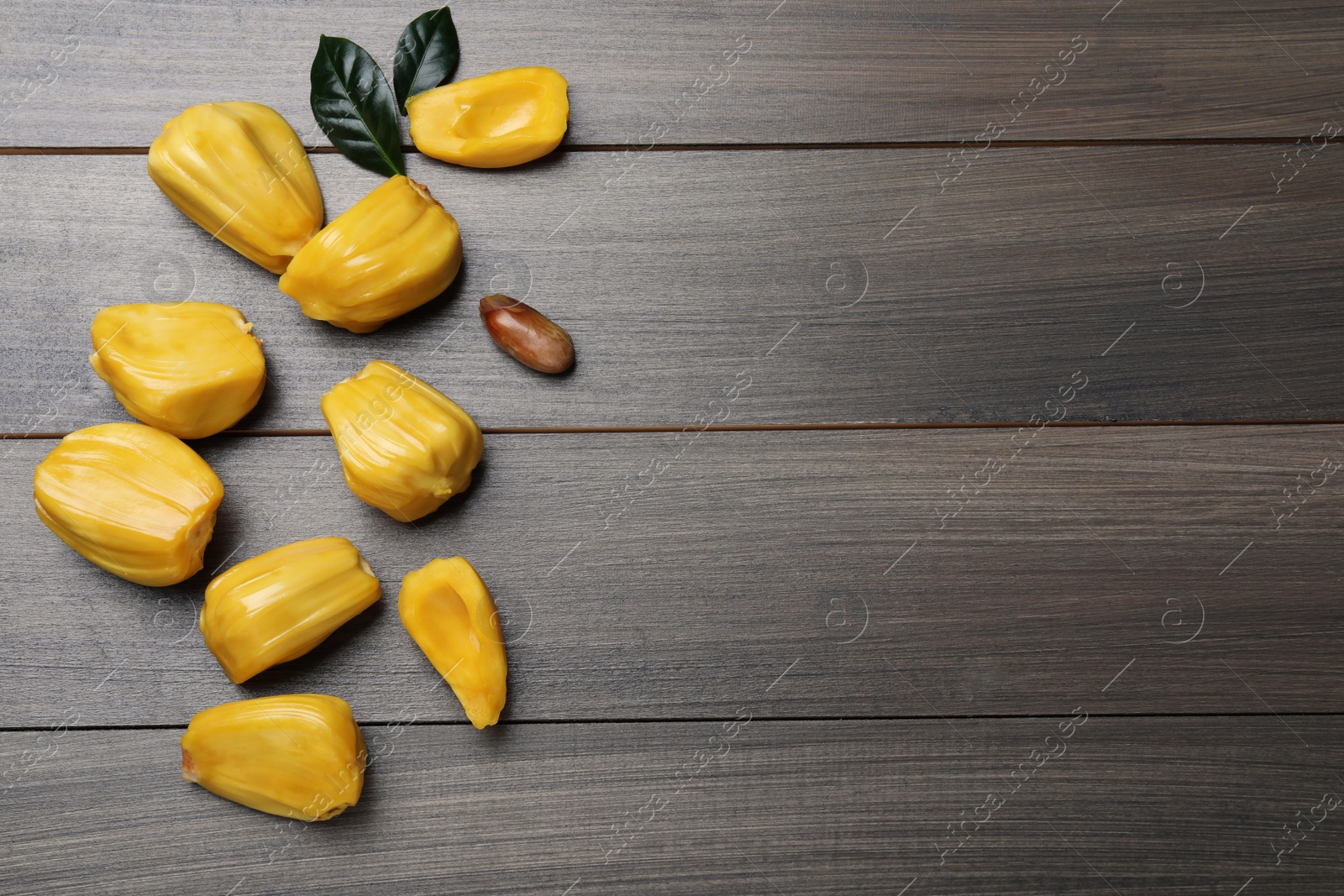 Photo of Delicious exotic jackfruit bulbs on wooden table, flat lay. Space for text