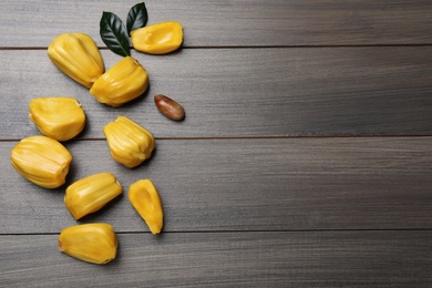 Delicious exotic jackfruit bulbs on wooden table, flat lay. Space for text