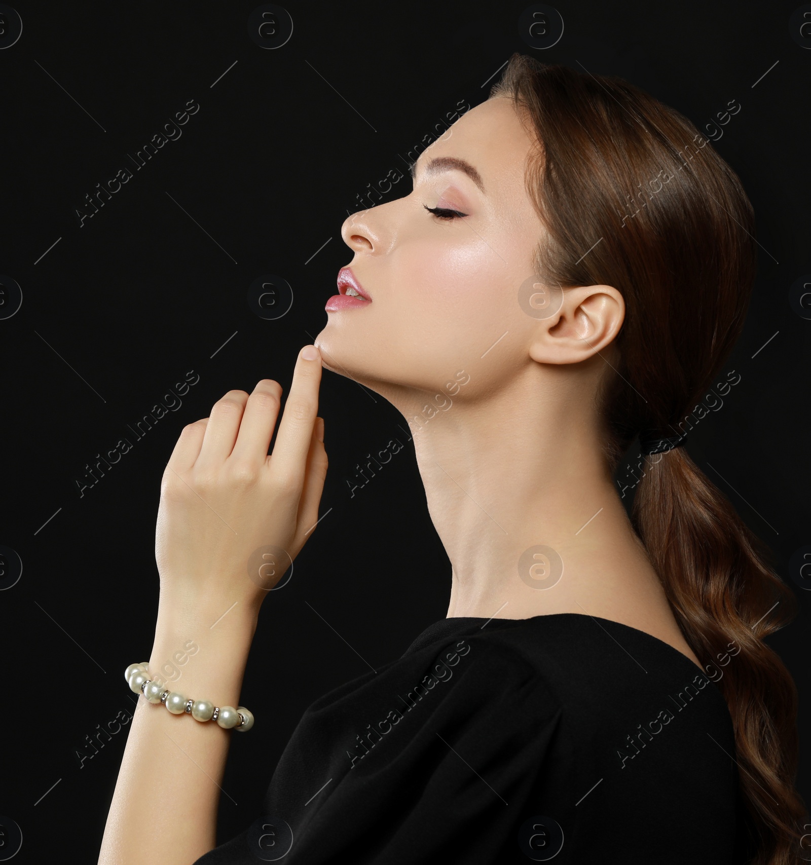 Photo of Young woman wearing elegant pearl bracelet on black background, space for text