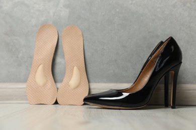 Photo of Orthopedic insoles near high heel shoes on floor