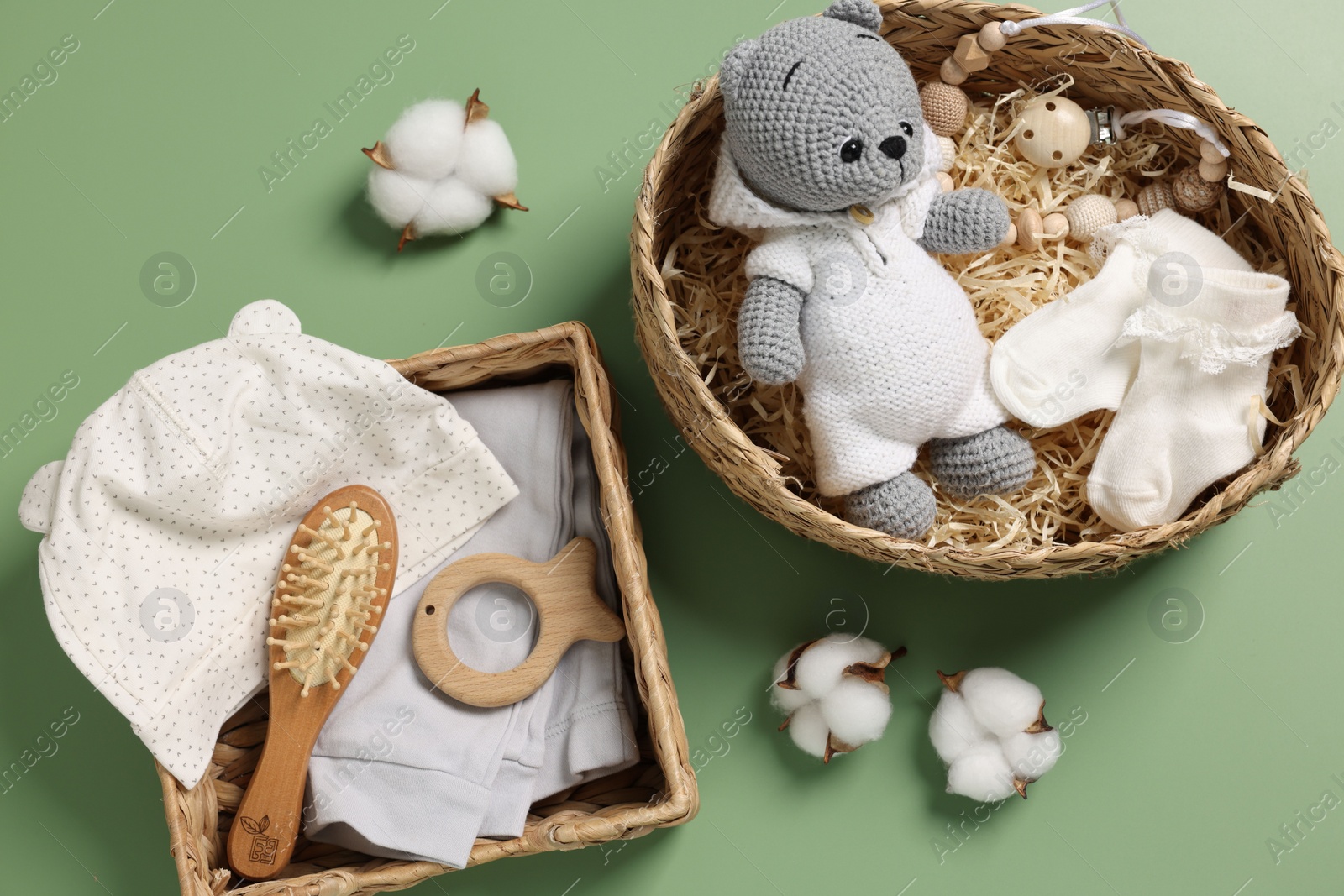 Photo of Different baby accessories, clothes and cotton flowers on green background, flat lay