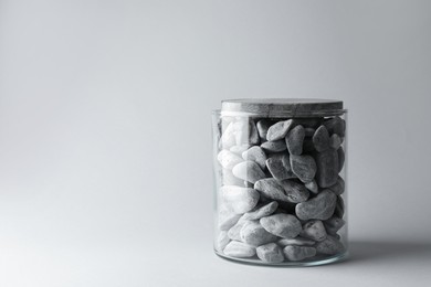 Photo of Presentation for product. Glass container with stones on light grey background. Space for text