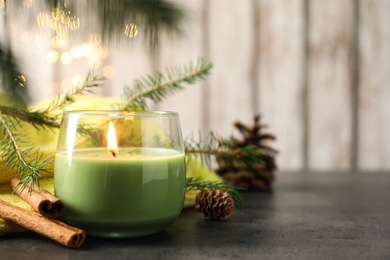 Composition with burning candle and pinecones on black table, space for text