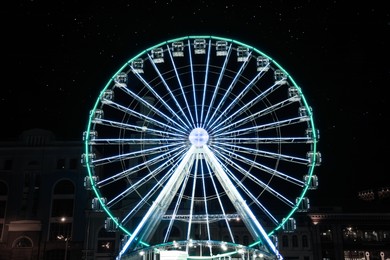 Photo of Beautiful glowing Ferris wheel on city street at night