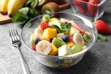 Delicious fresh fruit salad in bowl on grey table