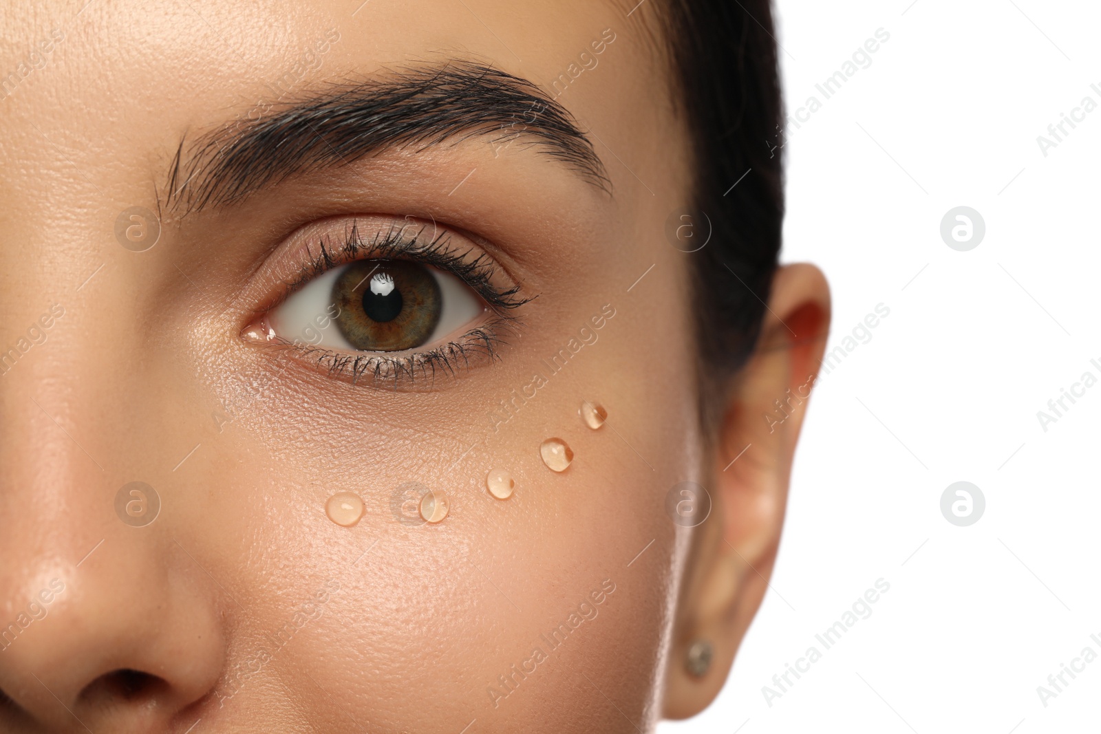Photo of Closeup view of young woman with gel on skin under eye against white background